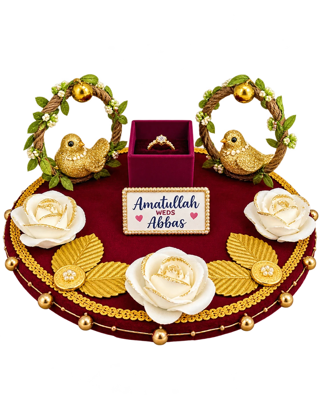 Round maroon velvet ring tray with two gold birds in rope wreaths, a ring box, white roses, gold leaves and a name plaque
