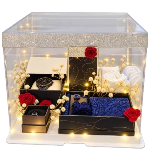 Acrylic display box with fairy lights holding a watch, ring, cufflinks, navy pocket squares and rolled white towels