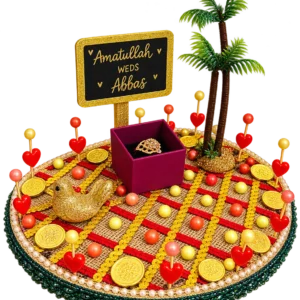 Round jute ring tray with red and gold trims, gold coins, a palm tree, a gold bird, heart picks, a ring box and a name board