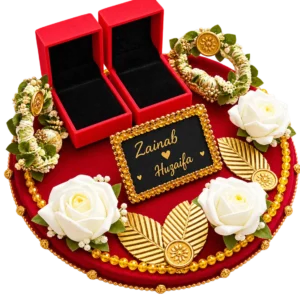 Round red velvet ring ceremony tray with two red ring boxes, gold leaves, white roses, gajra bracelets and a name plaque